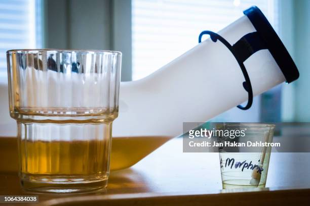 water glass, urine bottle and medicine cup with morphine on hospital table - urine cup stock pictures, royalty-free photos & images