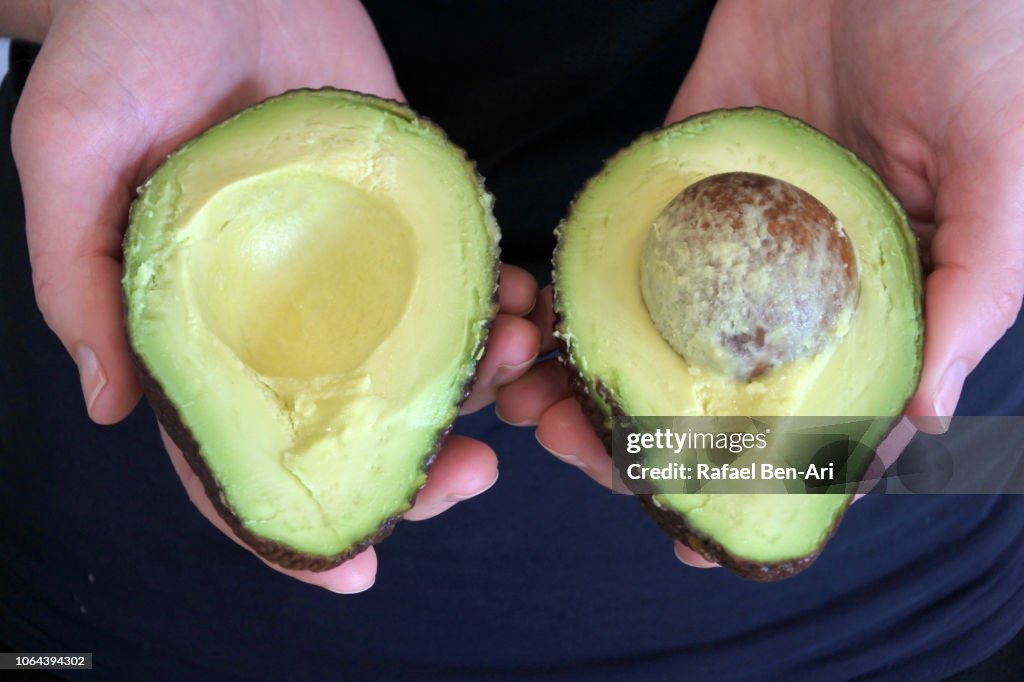 Woman Holding Two Half of Cut Avocado Fruit