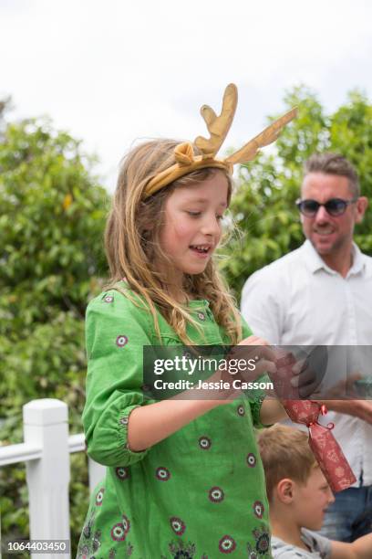 a girl wearing reindeer antlers looks at her christmas cracker - christmas crackers stock pictures, royalty-free photos & images