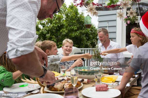 a family sit outside eating christmas lunch and pulling christmas crackers - family christmas stock pictures, royalty-free photos & images