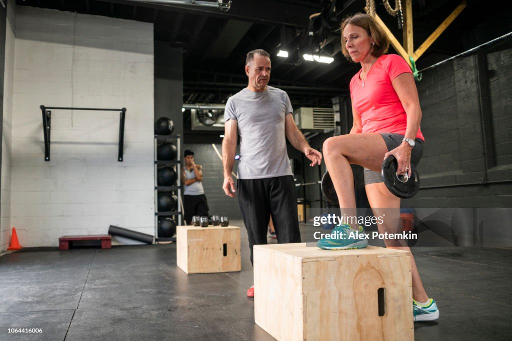 The senior 55-years-old Latino woman doing step-up with weight exercise in the gym