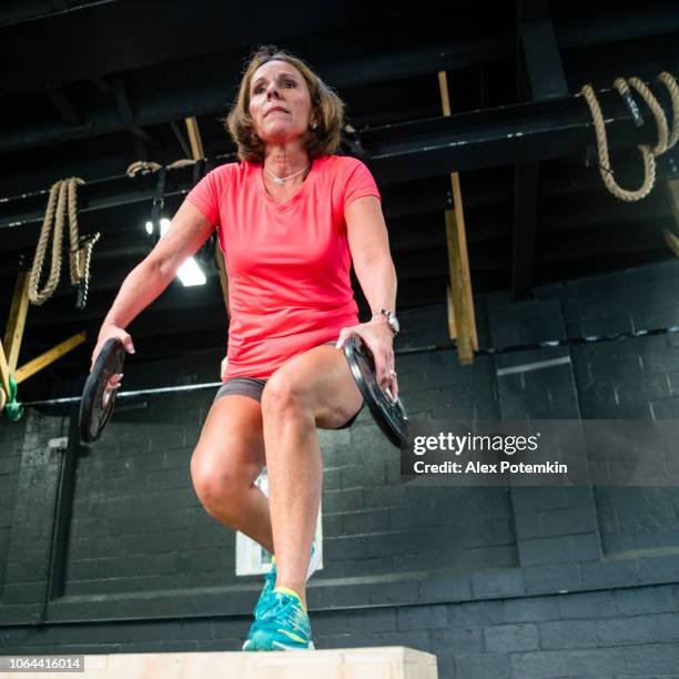 the senior 55-years-old latino woman doing step-up with weight exercise in the gym - alex potemkin or krakozawr latino fitness stock pictures, royalty-free photos & images