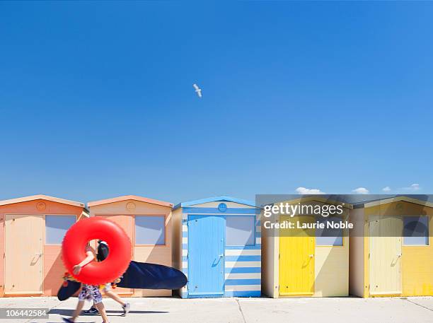 people with ring and surf board walking past huts - beach house 個照片及圖片檔