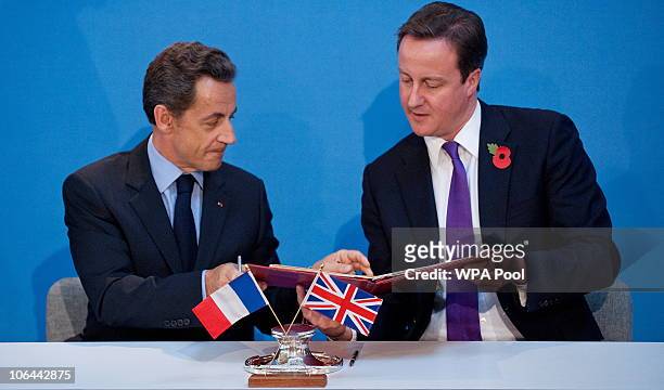 French President Nicolas Sarkozy , and British Prime Minister David Cameron exchange copies after signing a treaty during an Anglo-French summit, at...