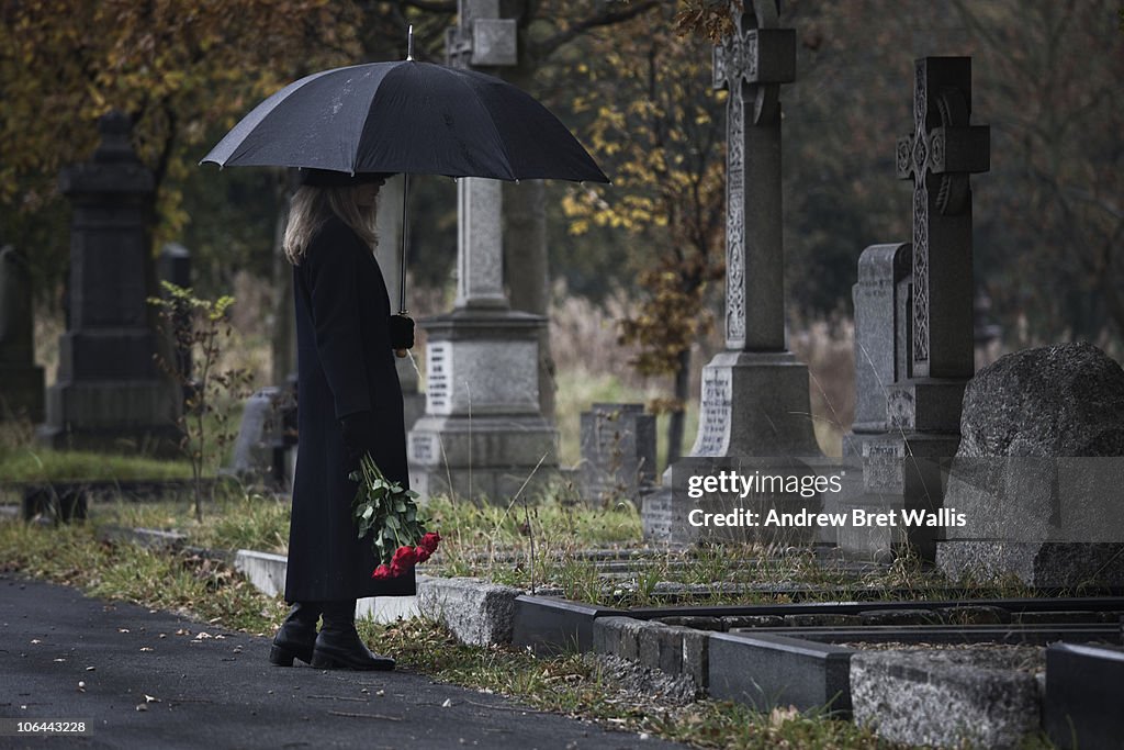 Widow bringing roses to a grave in a cemetery