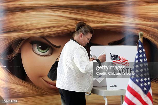 Maria Warmuz, of Lemont, Illinois, finishes casting her vote at the AMC Woodridge 18 Theatres in front of the eyes of a huge poster promoting...