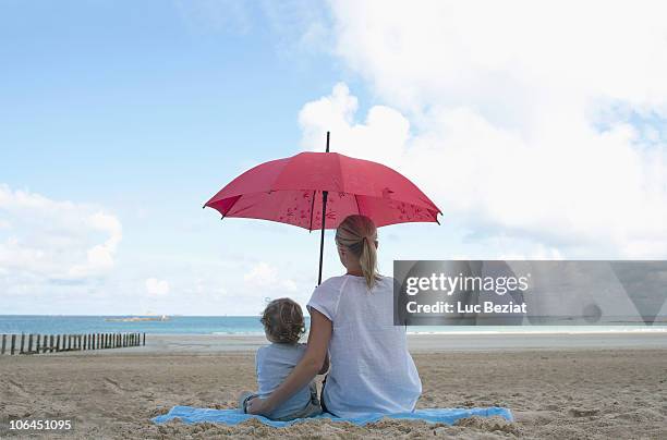 woman and son under a parasol - sombrilla playa fotografías e imágenes de stock
