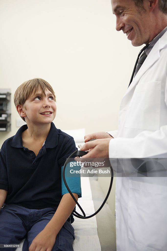 Doctor taking young boy's blood pressure