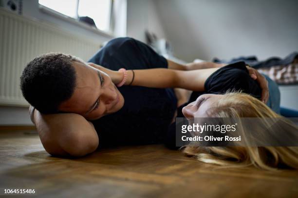 affectionate young couple lying on the floor at home - désir photos et images de collection