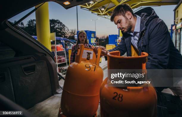 young couple buying lpg gas bottle at gas station - liquefied petroleum gas stock pictures, royalty-free photos & images
