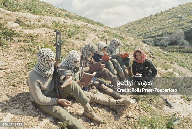 View of keffiyeh wearing Fatah guerilla recruits reading arabic translations of 'Quotations from Chairman Mao Tse-tung' whilst undergoing commando...