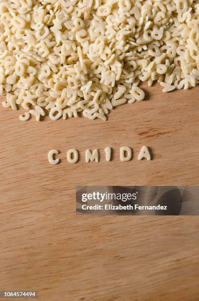 word "comida" made of alphabet pasta on wooden table background - pâtes alphabet photos et images de collection