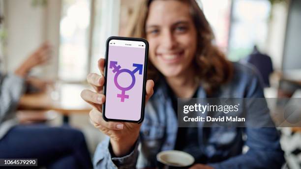 person in cafe showing a transgender sign on a mobile phone. - androgyn stockfoto's en -beelden