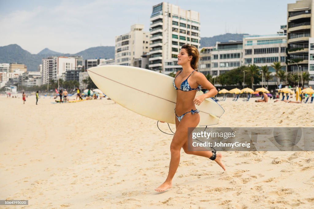 Joven corriendo hacia el mar con tabla de surf
