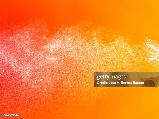 full frame of the textures formed  by the water jets to pressure with drops floating in the air of color white on a red and orange background - color explosion water stock-fotos und bilder