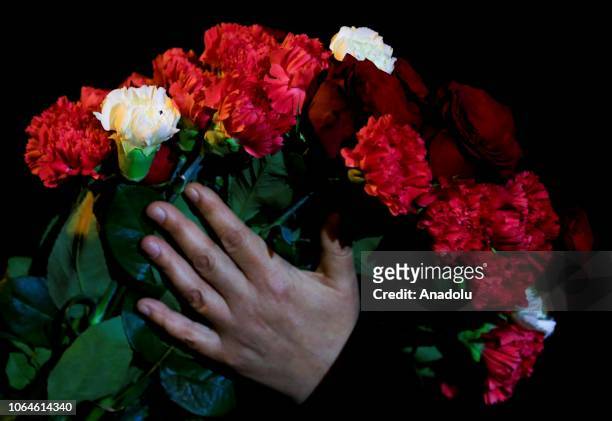 Person holds a bundle of flowers during a memorial for three Turkish girls, Bahide Arslan, Yeliz Arslan and Ayse Yilmaz, who died in a house that was...