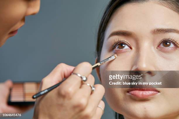 a make-up artist at work applying concealer under a models eyes - concealer stock pictures, royalty-free photos & images