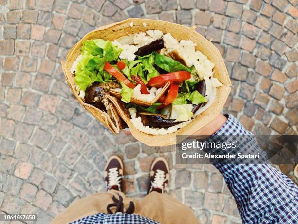 Eating big French crepe pancake with vegetables, salad and cheese, personal persoective view