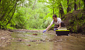 Woman ecologist taking samples of water from the creek