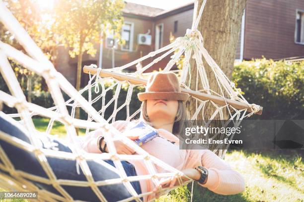 young woman lying down and sleeping on a hammock - garden hammock stock pictures, royalty-free photos & images