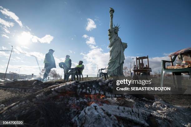 Yellow vests sit next to a replica of the Statue of the Liberty in Colmar, eastern France, on November 24, 2018 during a road blockade to protest...