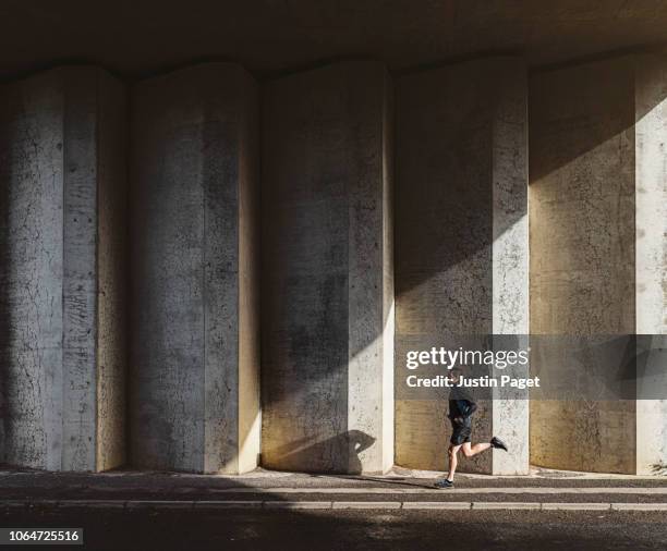 man running in concrete underpass - shadow people fitness stockfoto's en -beelden