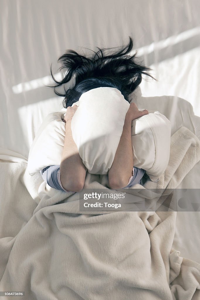 Female covering her face from a.m. sun with pillow