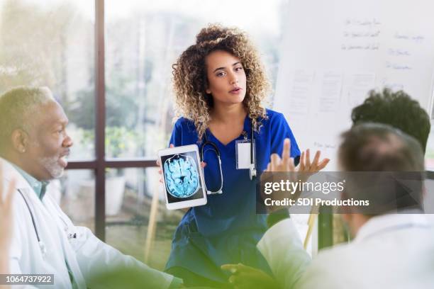 female doctor discusses brain x-ray during presentation - neurologist stock pictures, royalty-free photos & images