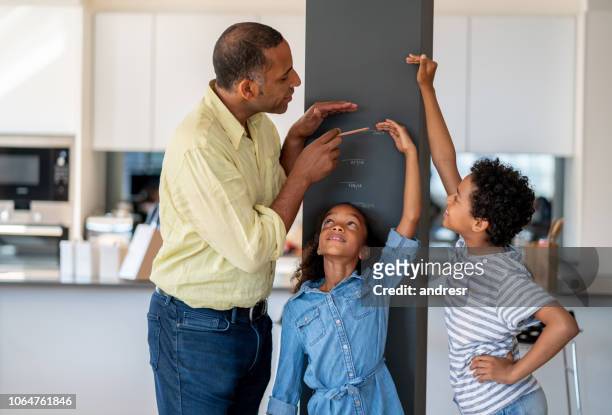 快樂的父親測量他的孩子在家裡 - high up 個照片及圖片檔
