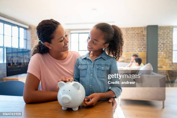 mutter und tochter in ein sparschwein geld sparen - family budget stock-fotos und bilder