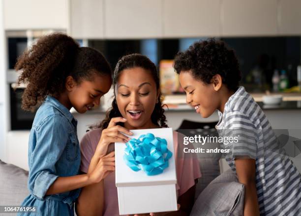 glückliche kinder überraschend ihre mutter mit einem geschenk zum muttertag - surprised mum stock-fotos und bilder