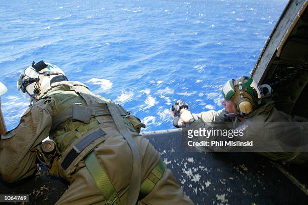 Helicopter crew chief Randall Elkins monitors a landing aboard the USS Lake Erie during the RIMPAC excercise operations July 11, 2002 near Oahu,...