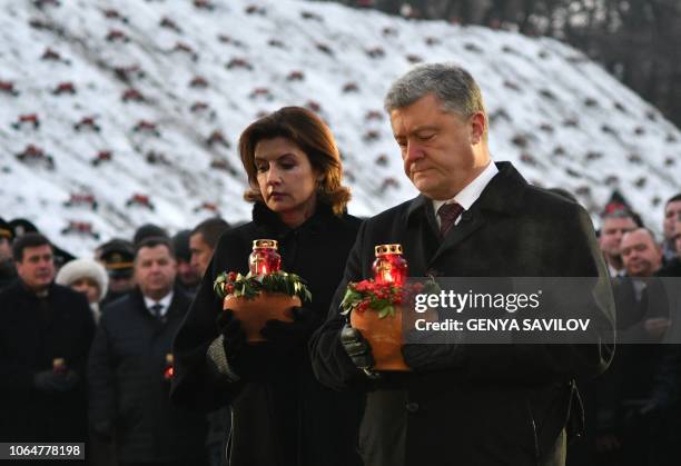 Ukrainian President Petro Poroshenko and his wife Maryna Poroshenko hold symbolic bowls with wheat and candles as they take part in a commemoration...