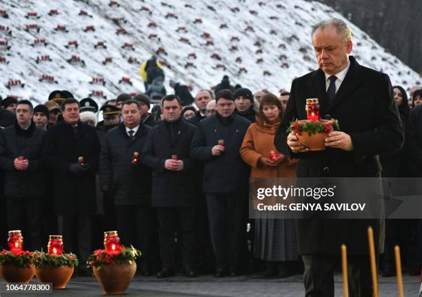 Slovak President Andrej Kiska holds a symbolic bowl with wheat and candles as he takes part in a commemoration ceremony at a monument to victims of...