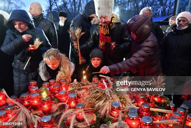People lay symbolic sheaves of wheat and lit candles during a commemoration ceremony at a monument to victims of the Holodomor famine of 1932-33 in...