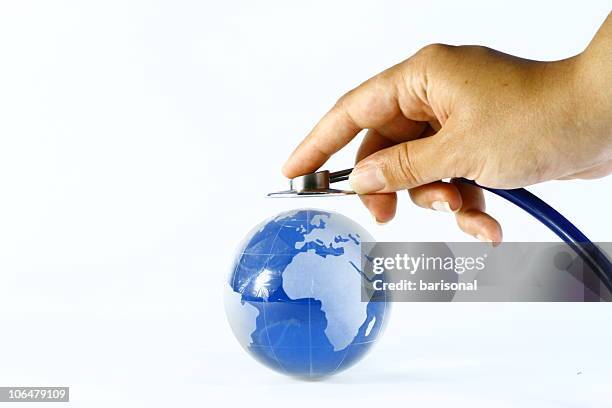 hand holds stethoscope up to world globe global healthcare - who 個照片及圖片檔
