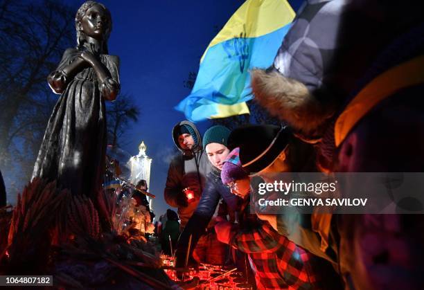 People lay symbolic sheaves of wheat and light candles during a commemoration ceremony at a monument to victims of the Holodomor famine of 1932-33 in...