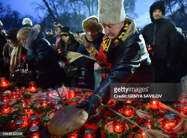 Man lays black bread and lit candles during a commemoration ceremony at a monument to victims of the Holodomor famine of 1932-33 in Kiev on November...