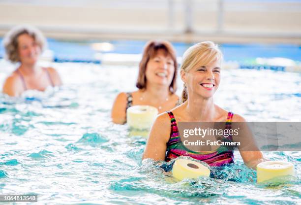 three women in a water exercise class - aqua aerobics stock pictures, royalty-free photos & images