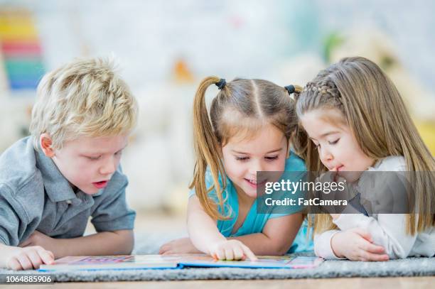 three toddlers reading a book - 2 year old book stock pictures, royalty-free photos & images
