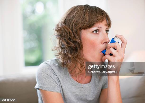 frau mittleren alters mit asthmainhalator - asthmainhalator stock-fotos und bilder