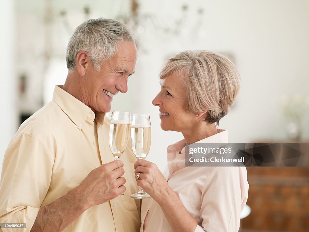 Senior man and mature woman toasting glass of wine, face to face