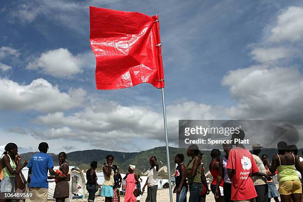 People stand around a red flag warning of an impending storm at the Corail-Cesselesse relocation camp November 3, 2010 in Port au Prince, Haiti....