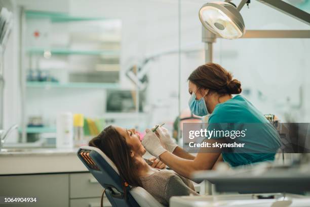 joven teniendo los dientes comprobados durante la cita en el consultorio del dentista. - dentist's office fotografías e imágenes de stock