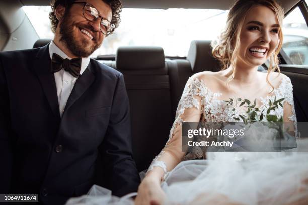 newlyweds holding hands in the backseat - wedding couple stock pictures, royalty-free photos & images