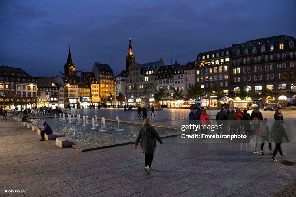 Kleber square with water fountain and pedestrians at night.