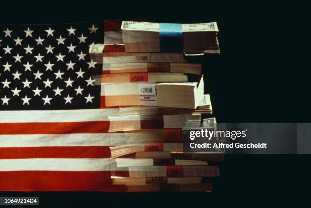 The American flag superimposed over a pile of American dollars banknotes, US, 1982.