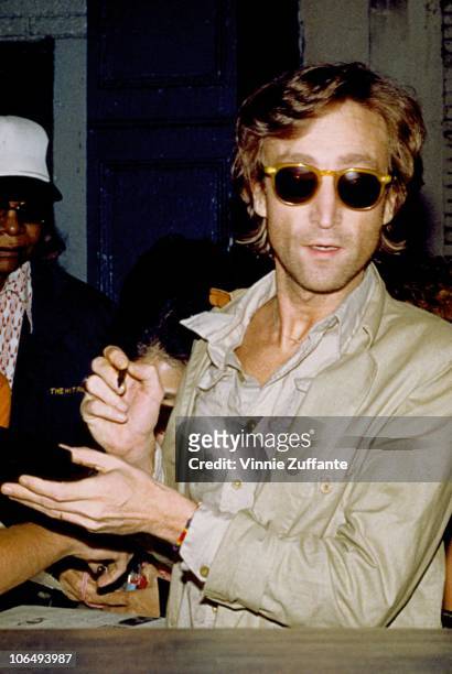 Former Beatle John Lennon signs autographs outside the Times Square recording studio 'The Hit Factory' after a recording session of his final album...