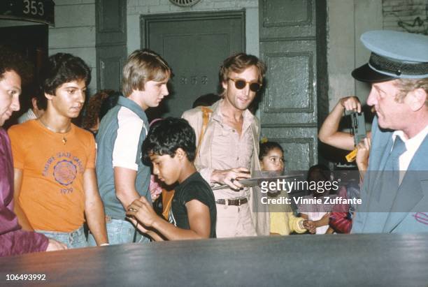 Former Beatle John Lennon signs autographs outside the Times Square recording studio 'The Hit Factory' after a recording session of his final album...
