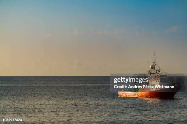 shiny and calm atlantic ocean with red lonely trawler - romatic scene - fishing boat fotografías e imágenes de stock